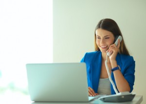Portrait young woman on phone in front of a laptop computer